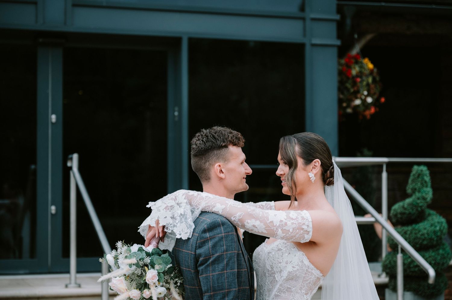 A romantic wedding moment captured outside a building with holiday decorations and a festive wreath visible.