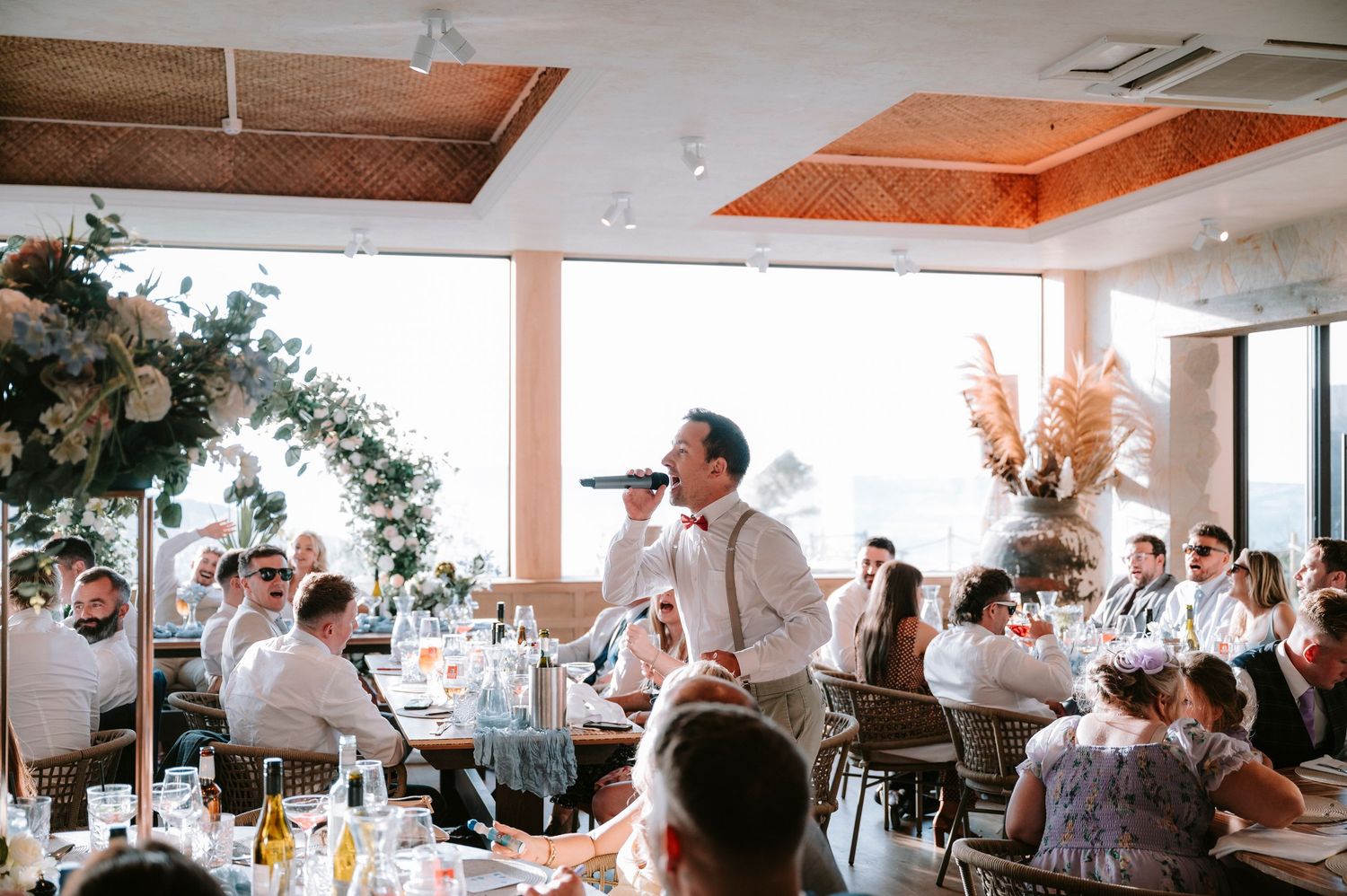 Wedding reception venue with wooden ceiling beams and natural light streaming through windows.