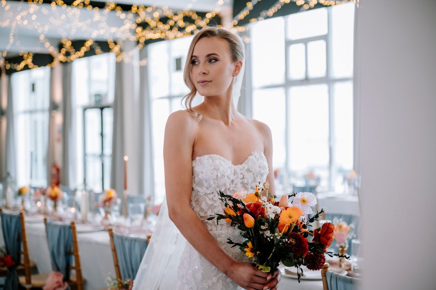 A stunning white wedding dress with intricate lace details and a colorful autumn bouquet.