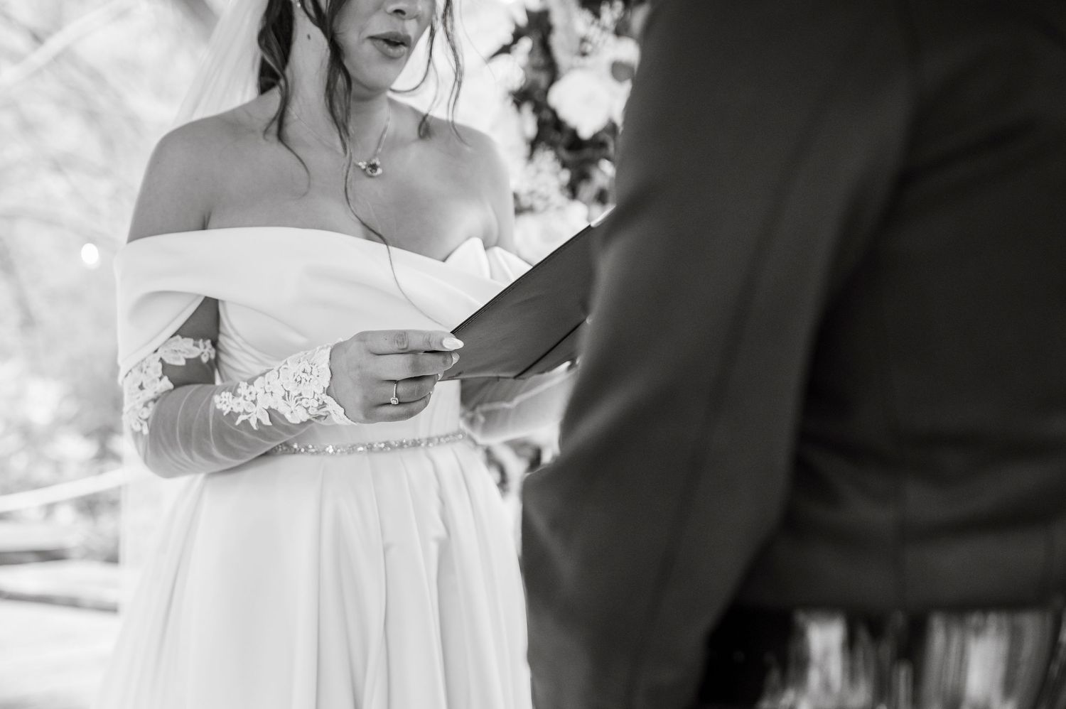 Couple signing wedding documents at a rustic wooden table during their ceremony.