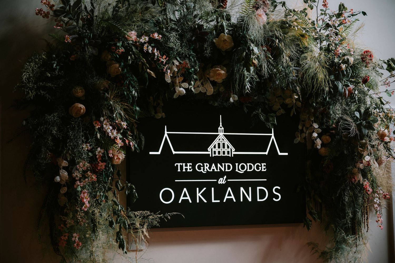 Floral arch decorations with venue logos for The Grand Lodge and Oaklands.