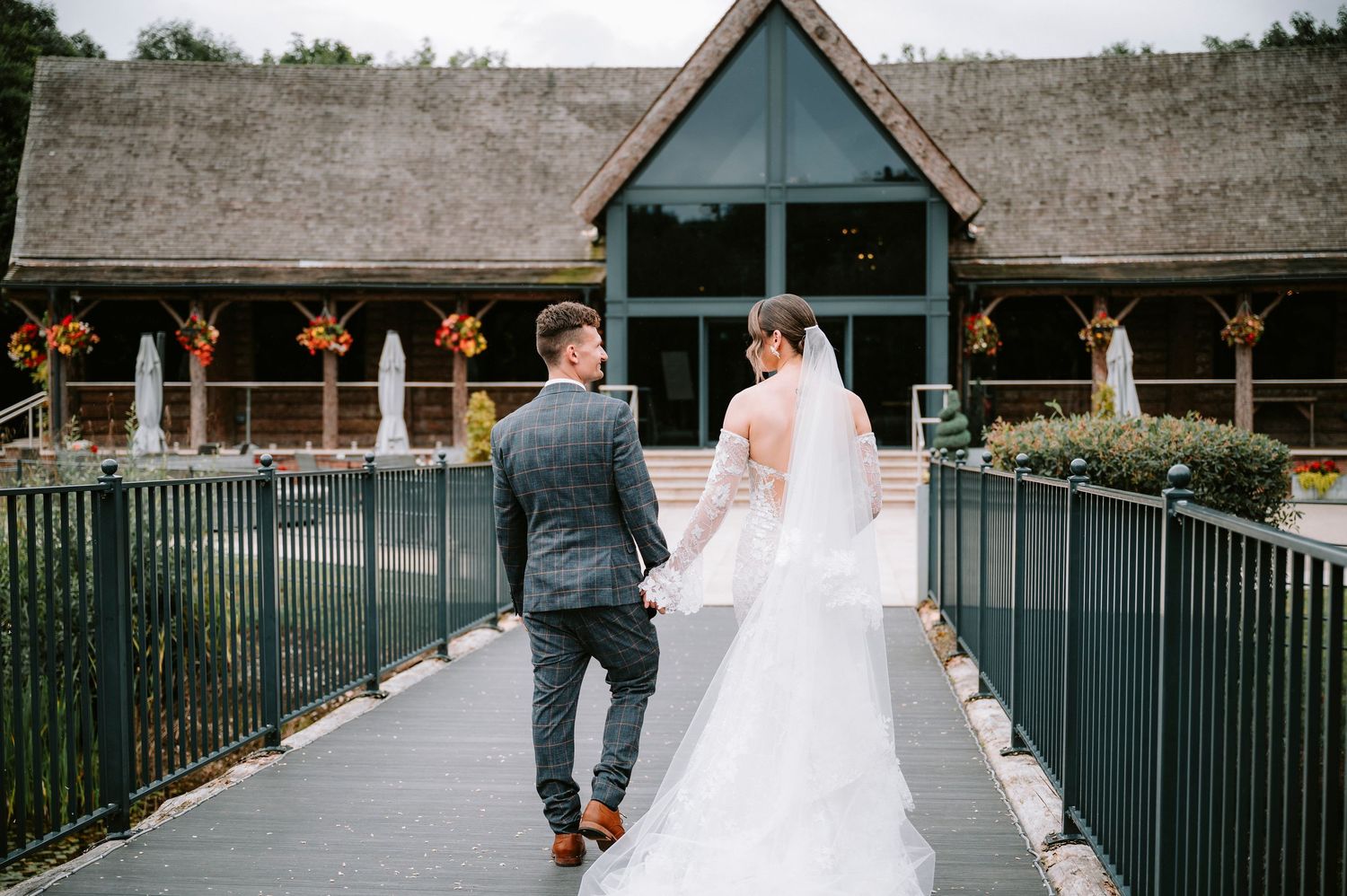 Wedding party walking along a modern venue exterior with glass and metal architecture.