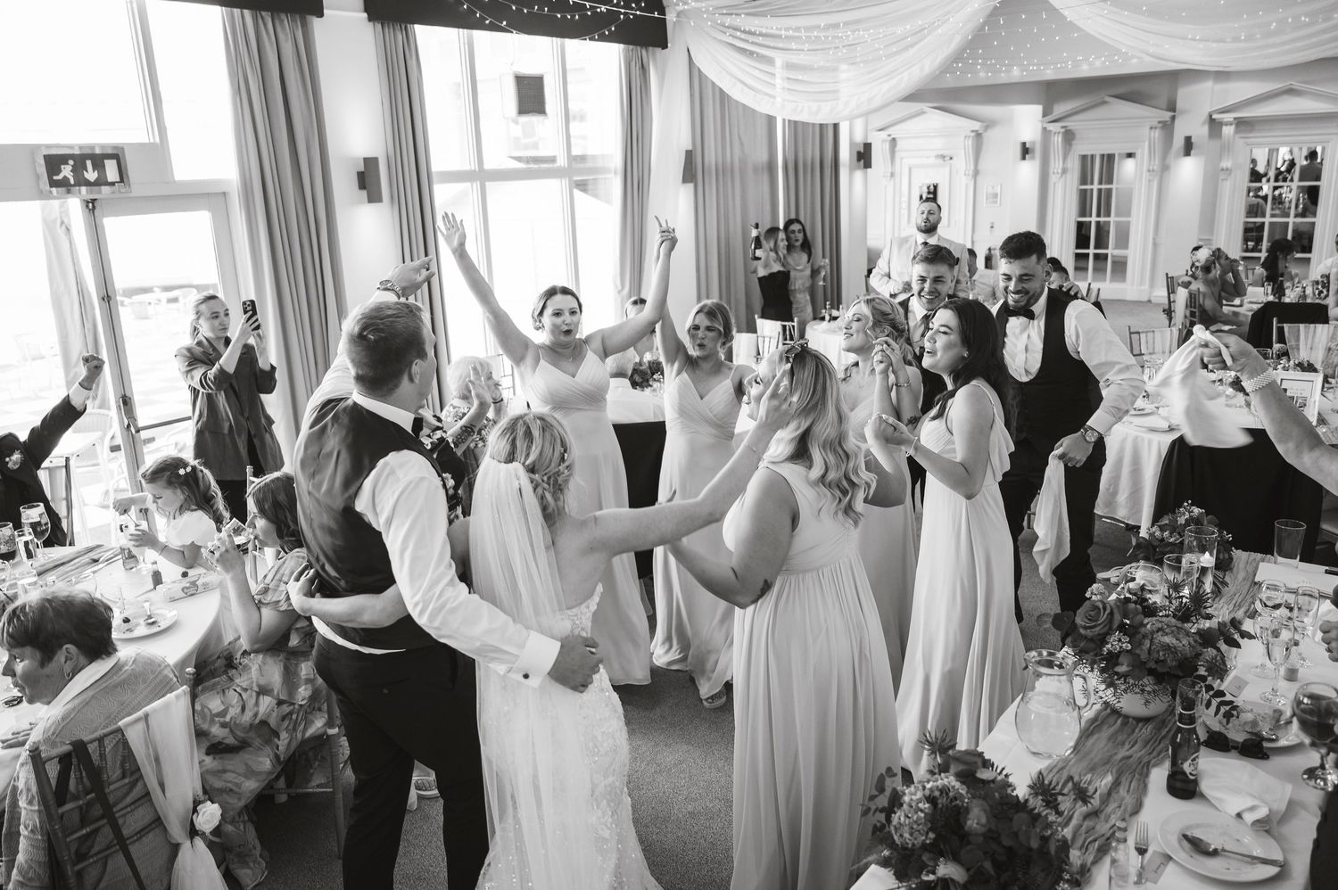 Wedding guests participate in celebratory napkin waving during indoor reception.