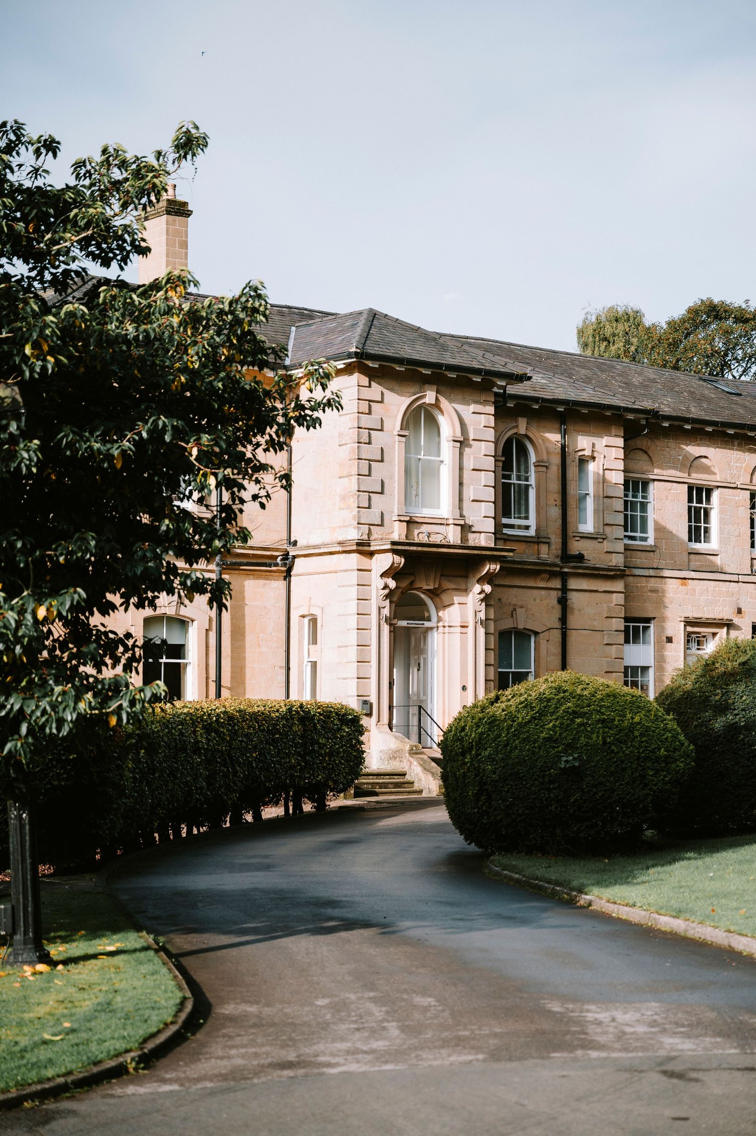 Elegant stone mansion with curved driveway and landscaped grounds shown from multiple exterior angles.