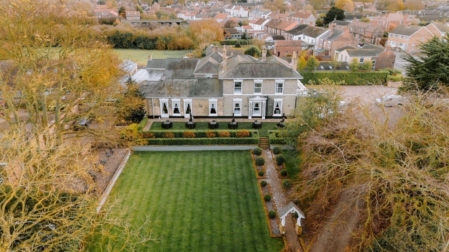 Aerial view of a stately home with perfectly maintained gardens and grounds.