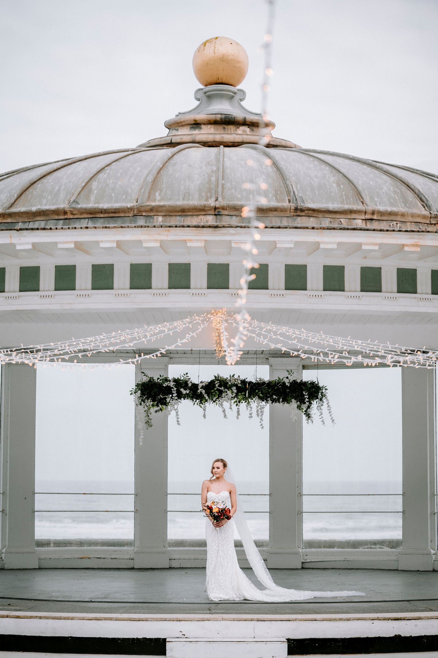 Elegant domed pavilion with crystal chandelier and ocean view for wedding ceremony.