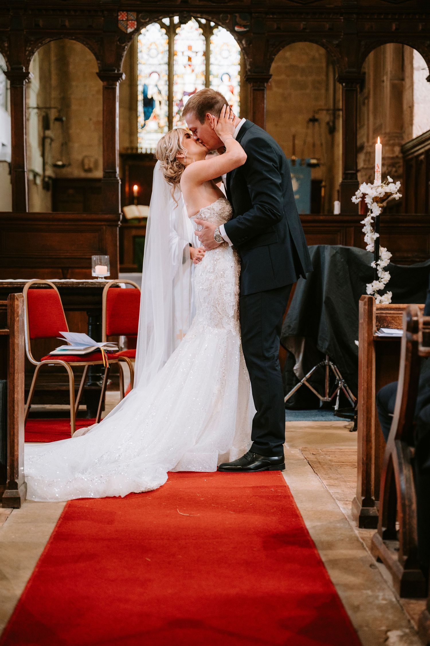 Intimate wedding ceremony moments on a red carpet aisle in a historic stone church.