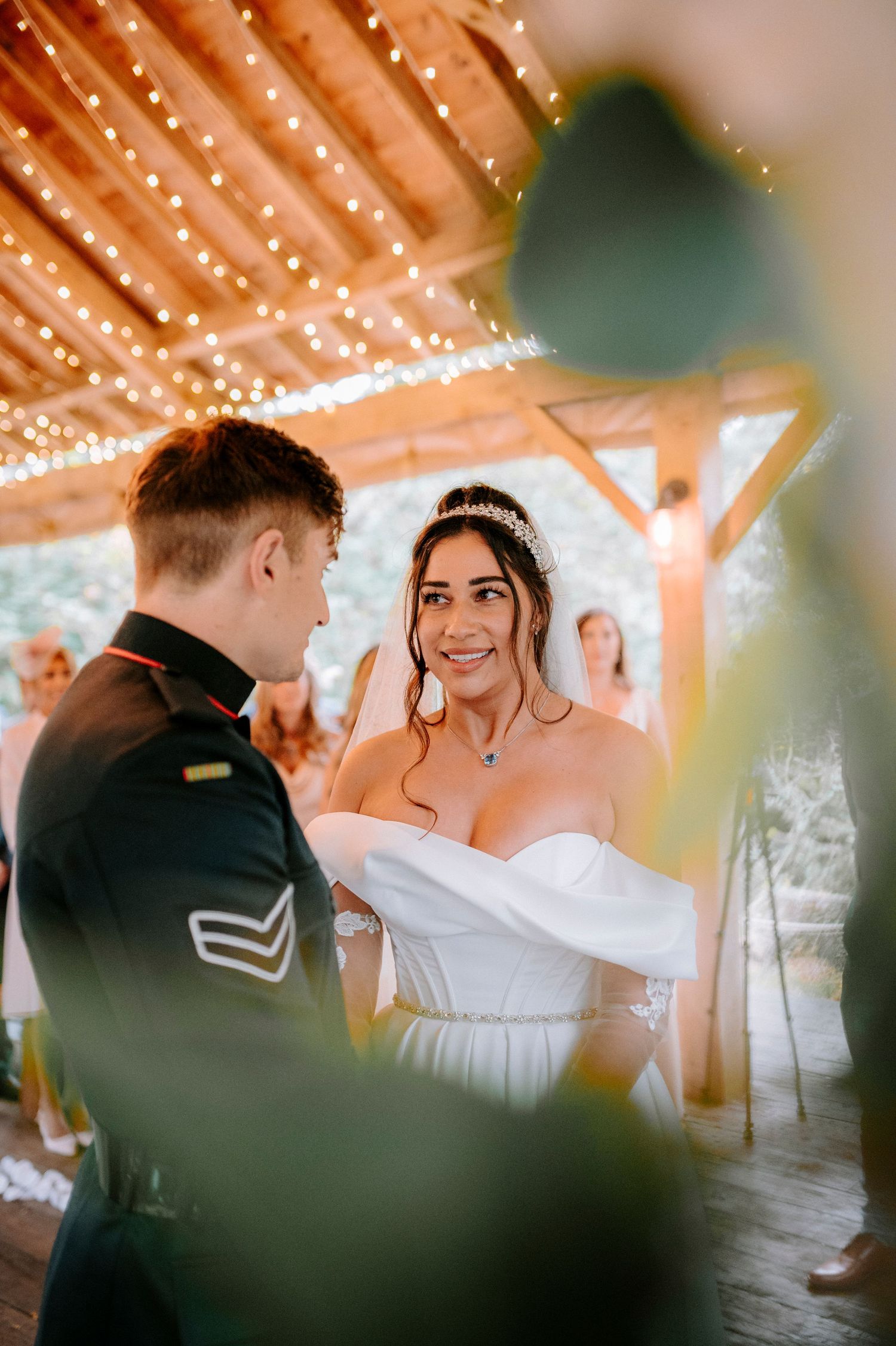 Wedding ceremony under twinkling lights with couple exchanging vows.