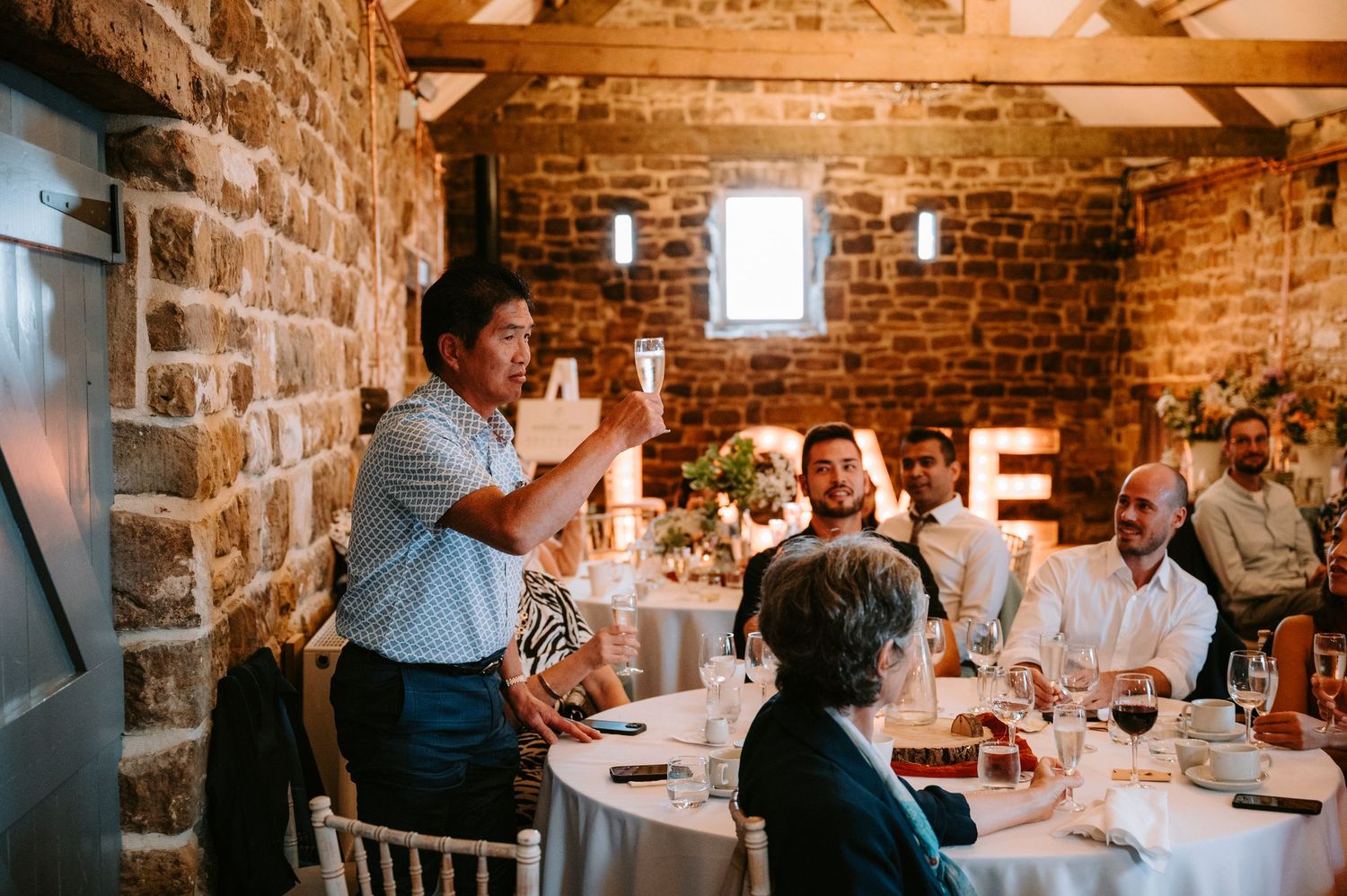 Rustic barn wedding reception venue with exposed brick walls and wooden beams.
