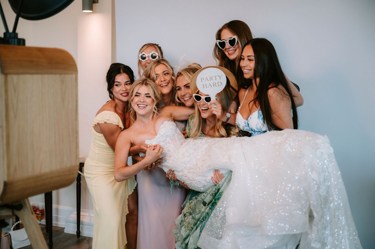 Bridal party in mix of coral and floral dresses pose for fun group photos.