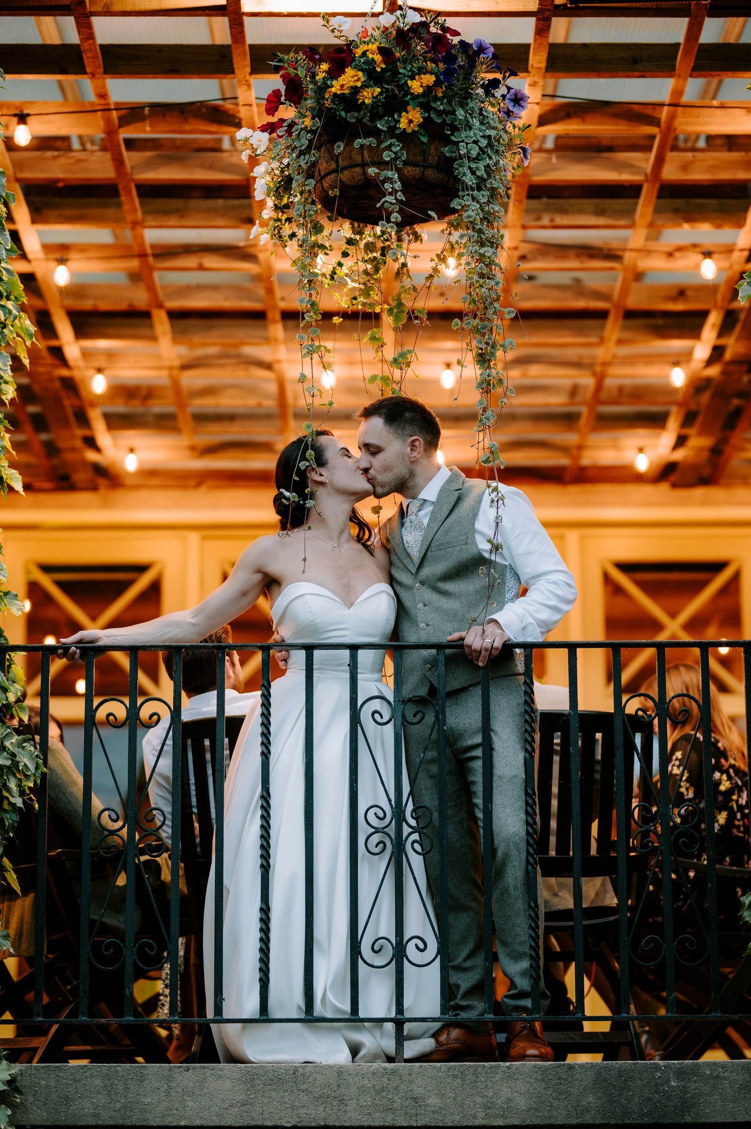 Romantic evening portrait of a couple embracing on a balcony with twinkle lights.