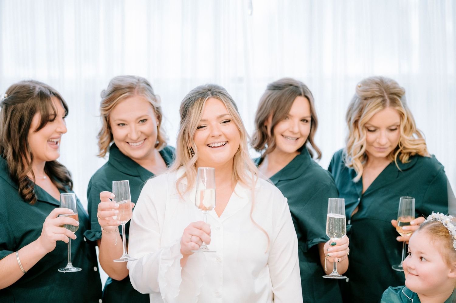 Wedding party members in matching green robes toast and celebrate together.
