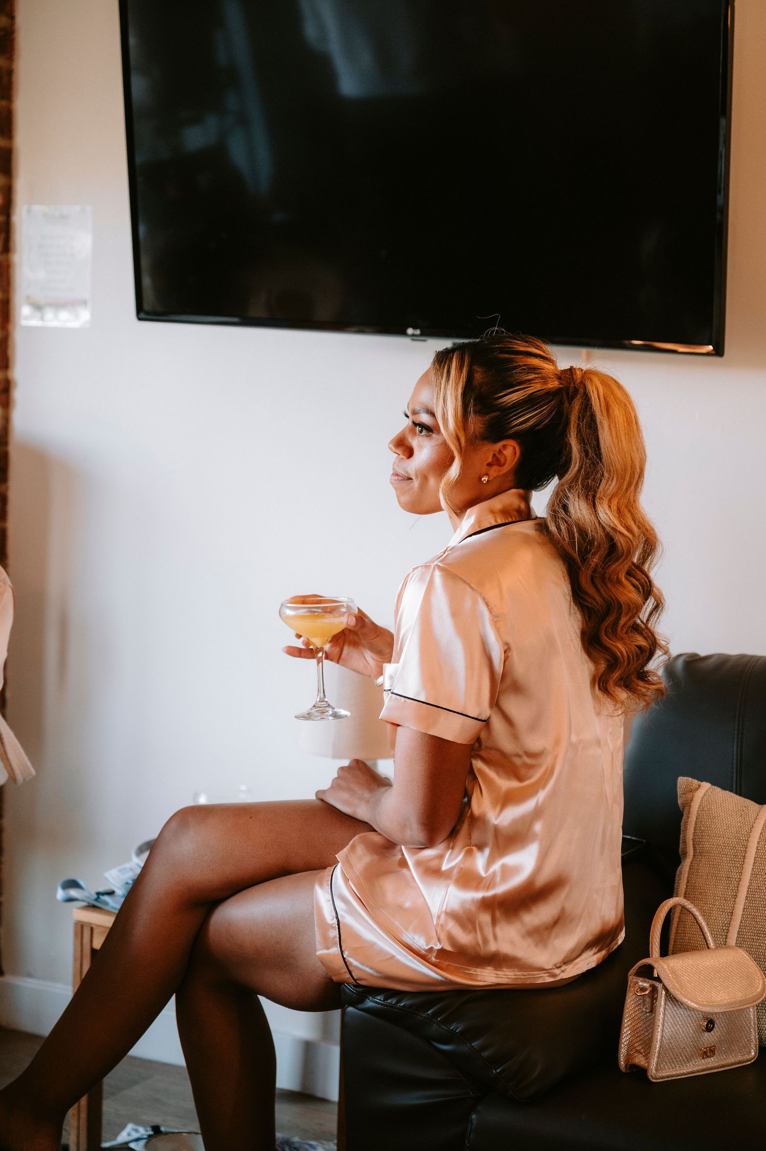 Woman in silk robe holding champagne glass while getting ready for special event.