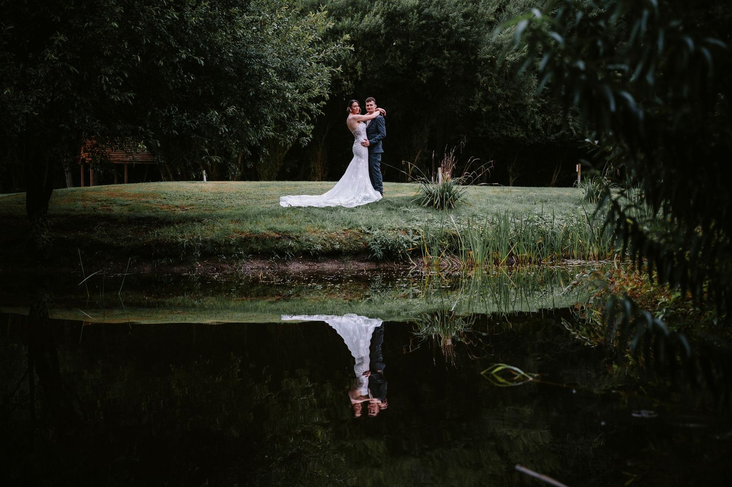 Artistic wedding photography series showing couple in natural outdoor setting with pond reflection.