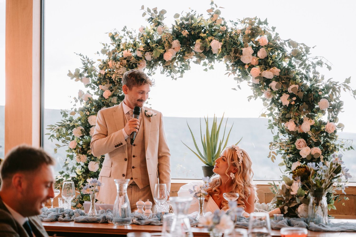 Wedding reception table decorated with floral arrangements and elegant place settings.