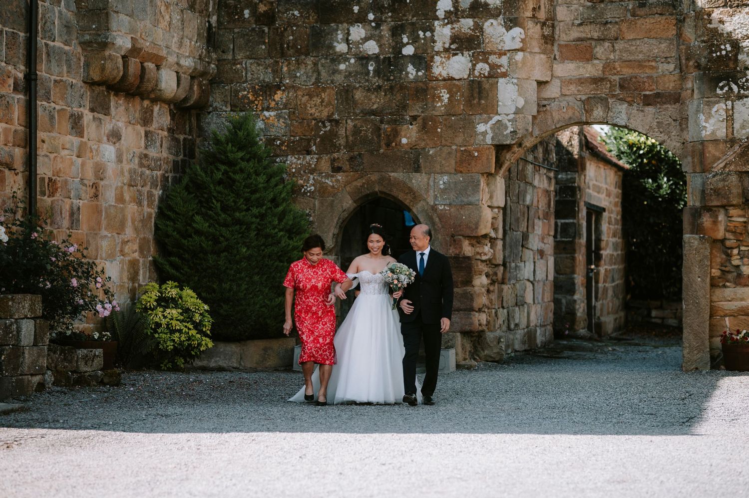 Wedding party gathering against a historic stone wall exterior.
