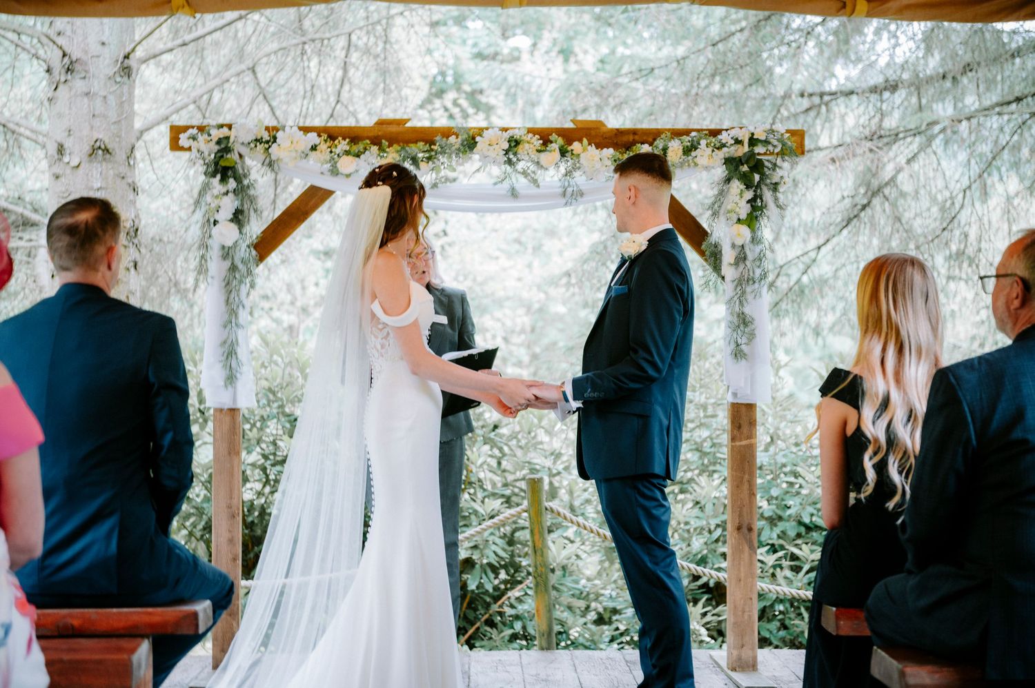 Wedding ceremony space decorated with white draping and floral arrangements.