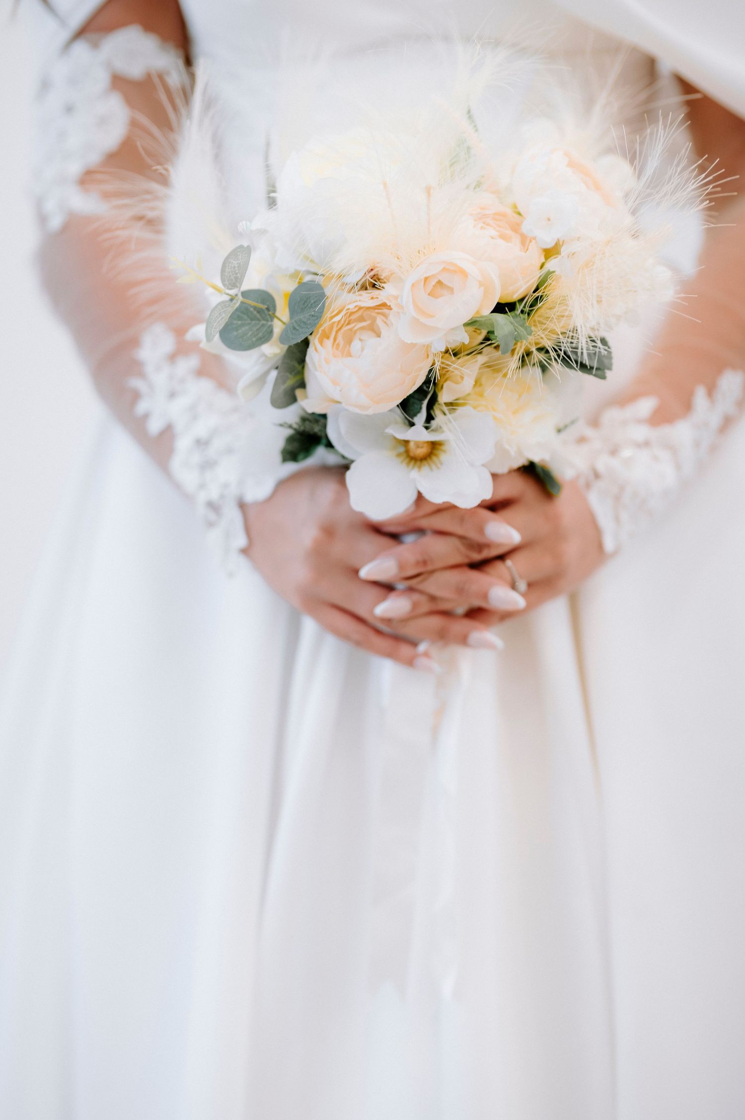 Close-up of delicate peach and white bridal bouquet with greenery accents.