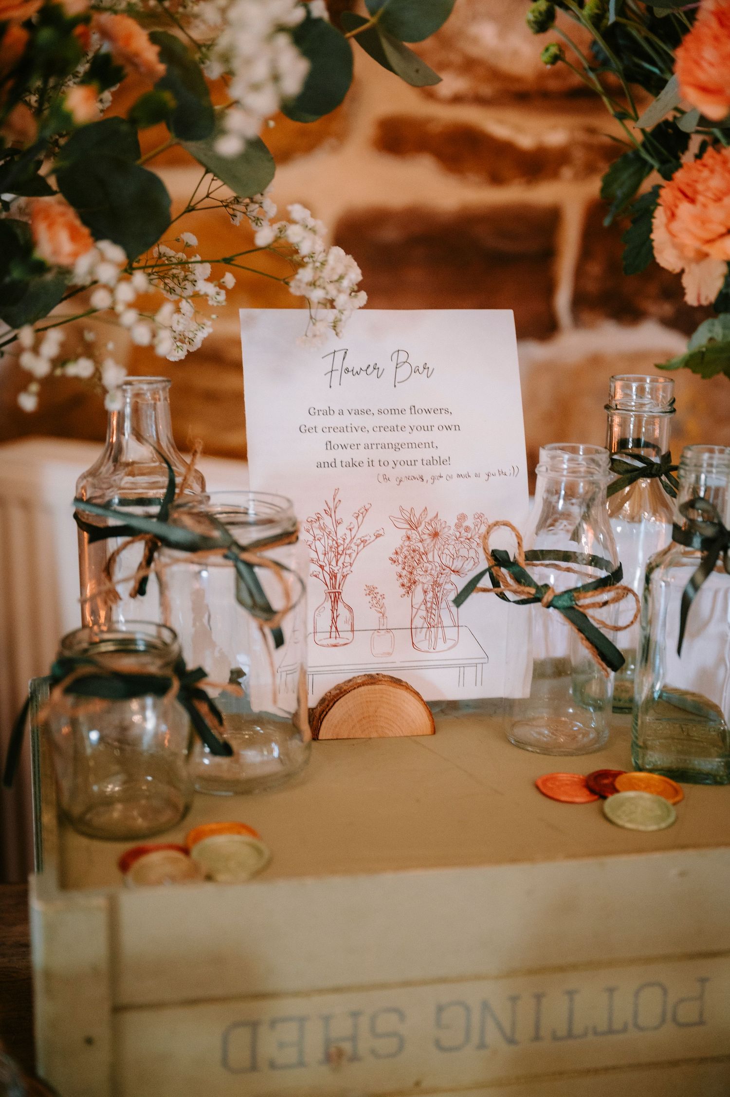 Rustic wedding table decor with glass jars, name cards, and floral arrangements on a vintage wooden surface.