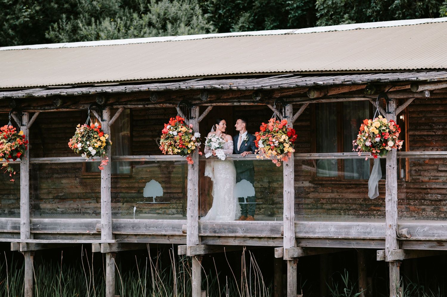 Rustic wooden deck railing decorated with colorful hanging flower baskets and white lanterns creates a charming outdoor space.