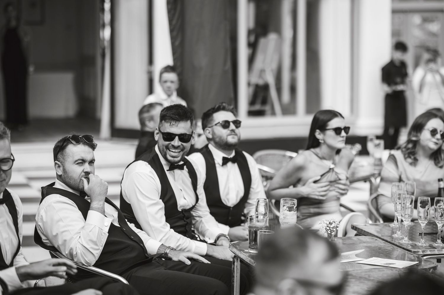 Black and white photo of wedding guests laughing and enjoying the reception.