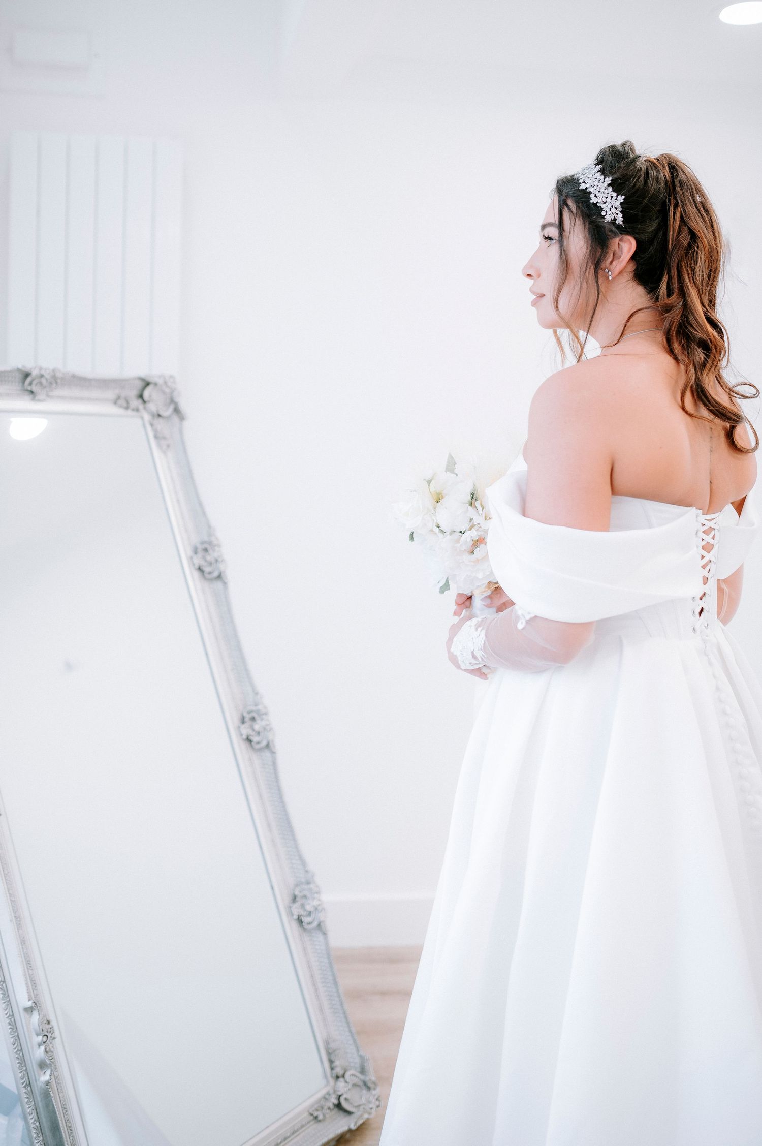 Ethereal bridal portraits against white walls showing flowing wedding dress details.