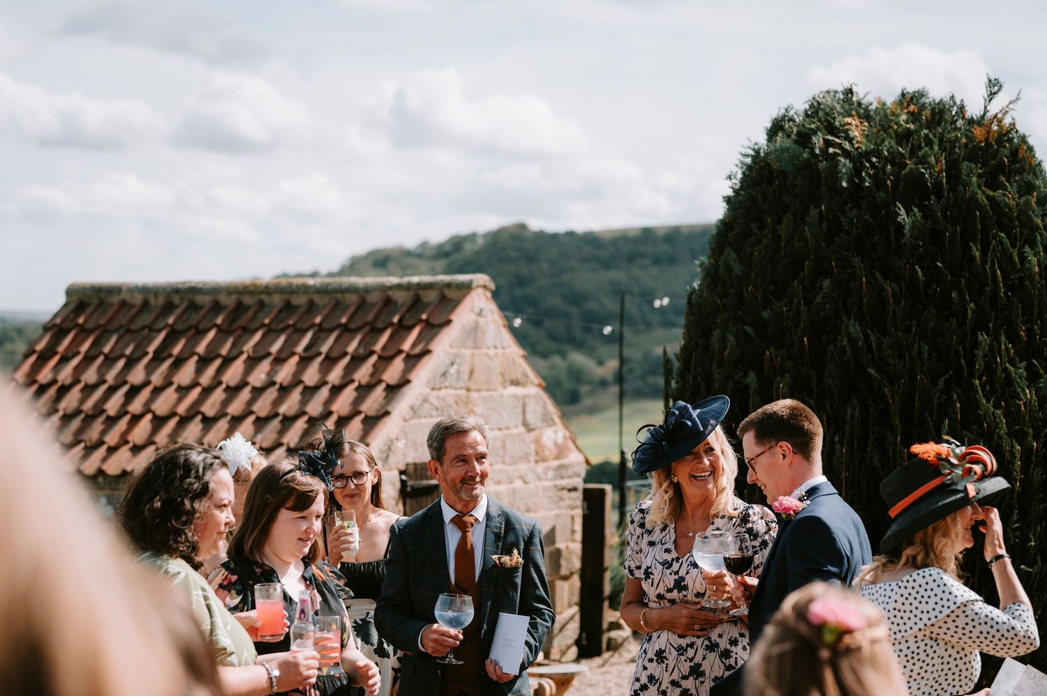 Wedding guests enjoying drinks and conversation at an outdoor venue with mountain views.