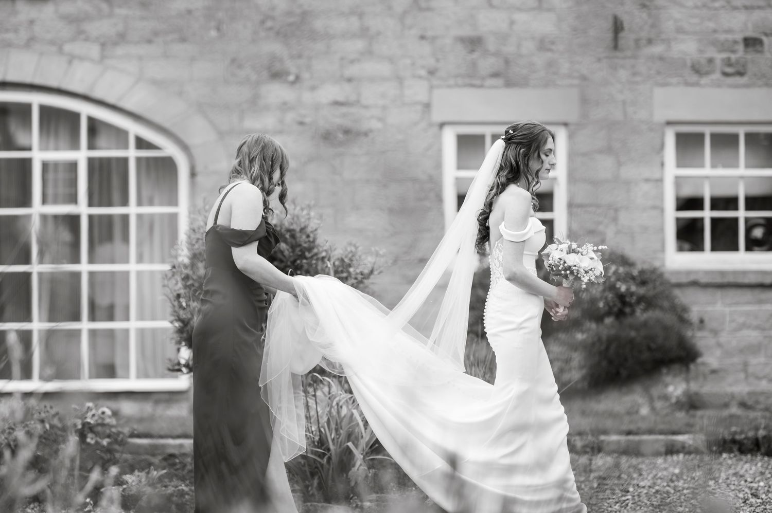 Black and white wedding photos showing a flowing veil against a stone building backdrop.