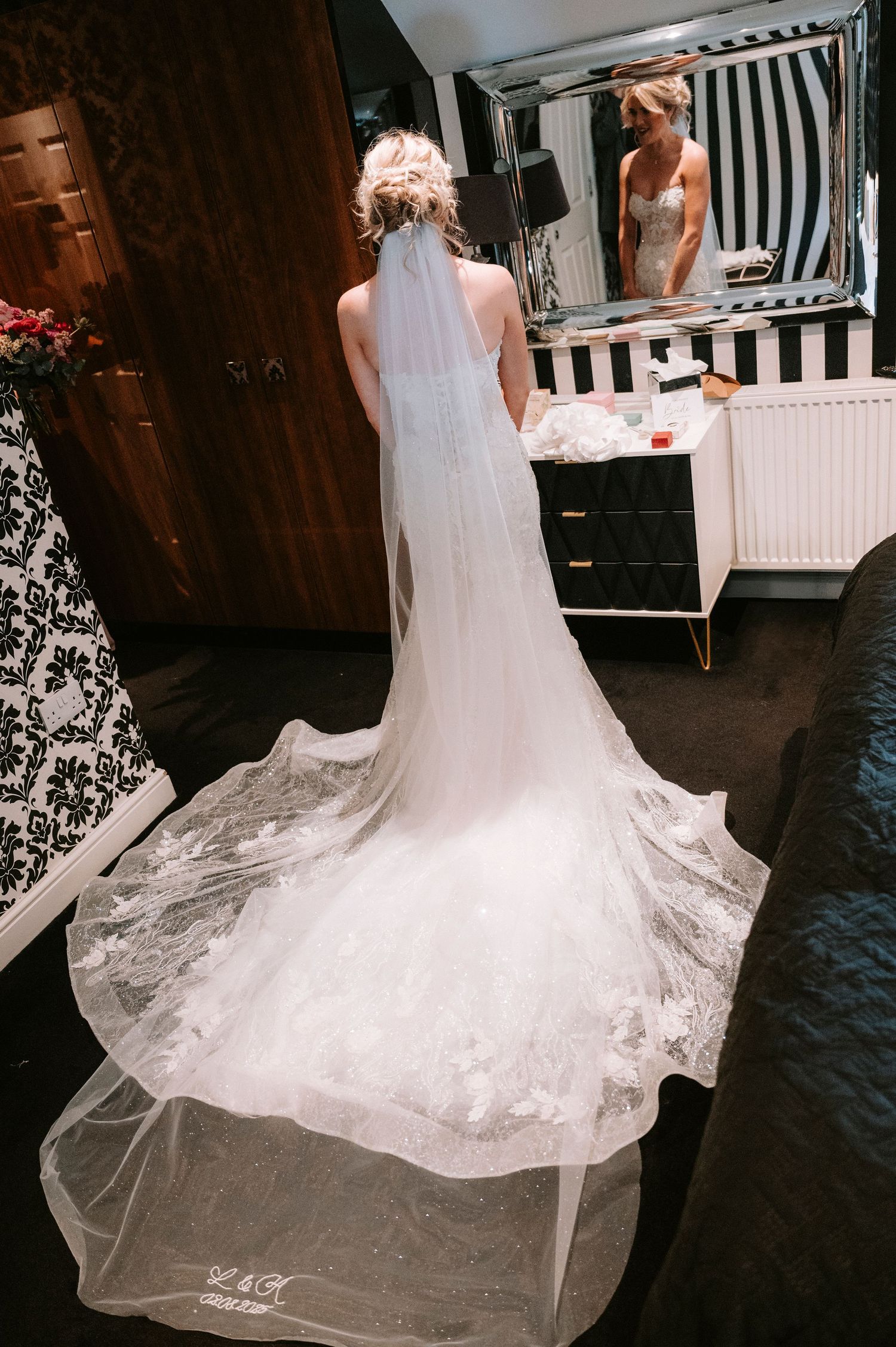 Beautiful lace wedding dress train flowing across a dark floor.