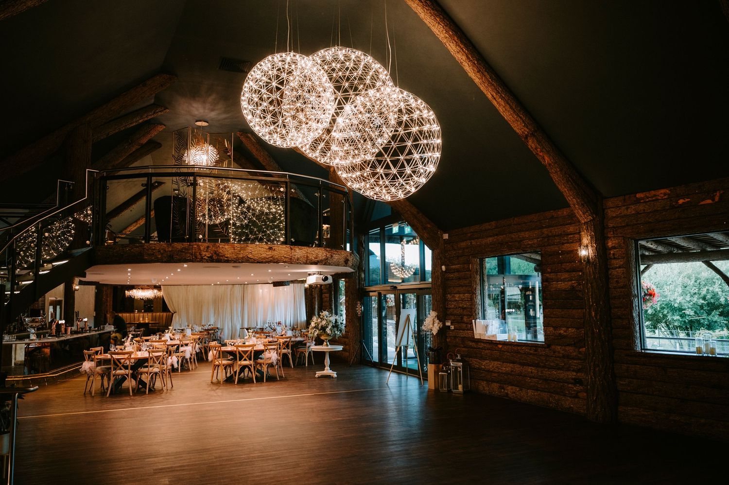 Elegant rustic wedding reception venue with hanging crystal chandeliers and wooden beam ceiling.
