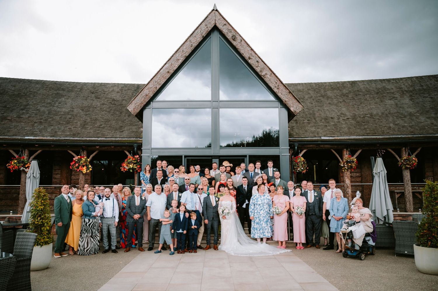 Wide view of a modern white wedding venue with guests gathered outside.