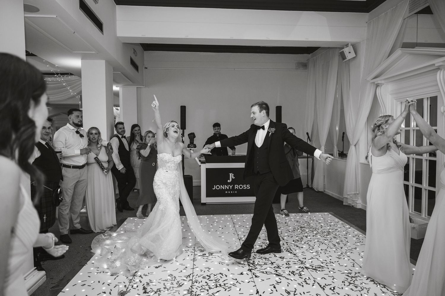 Wedding reception dance floor filled with guests celebrating under exposed beam ceilings.