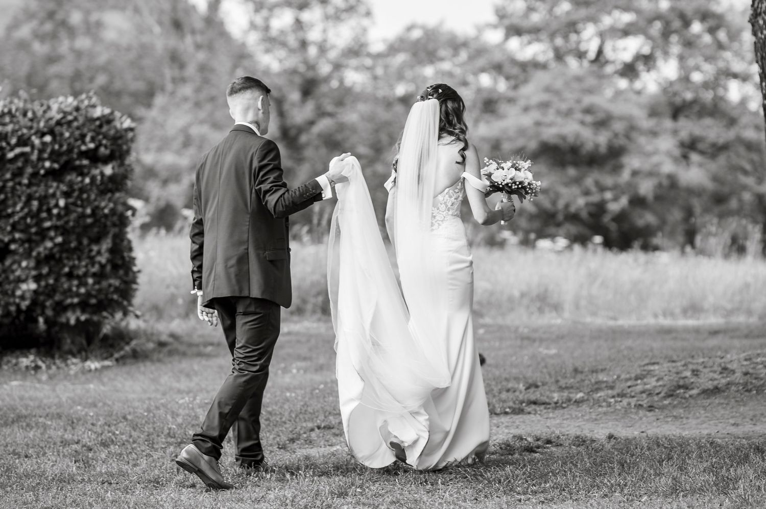 Black and white wedding photos showing a couple walking through a garden setting.