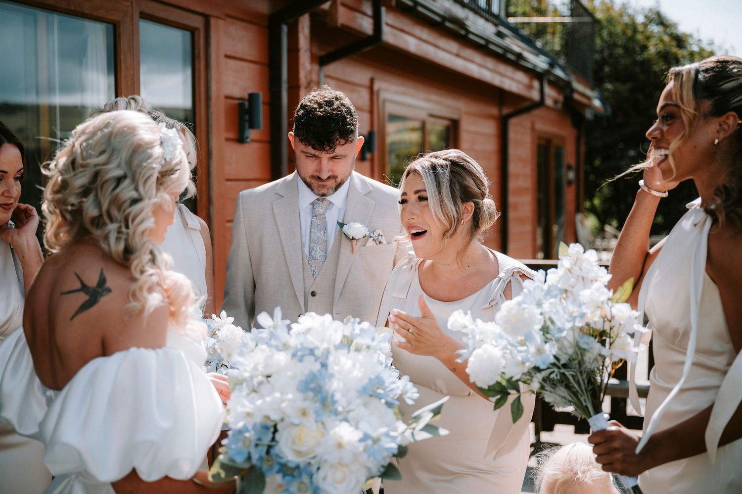 Wedding party celebrates outdoors with festive white smoke bombs creating dramatic effect against brick building.
