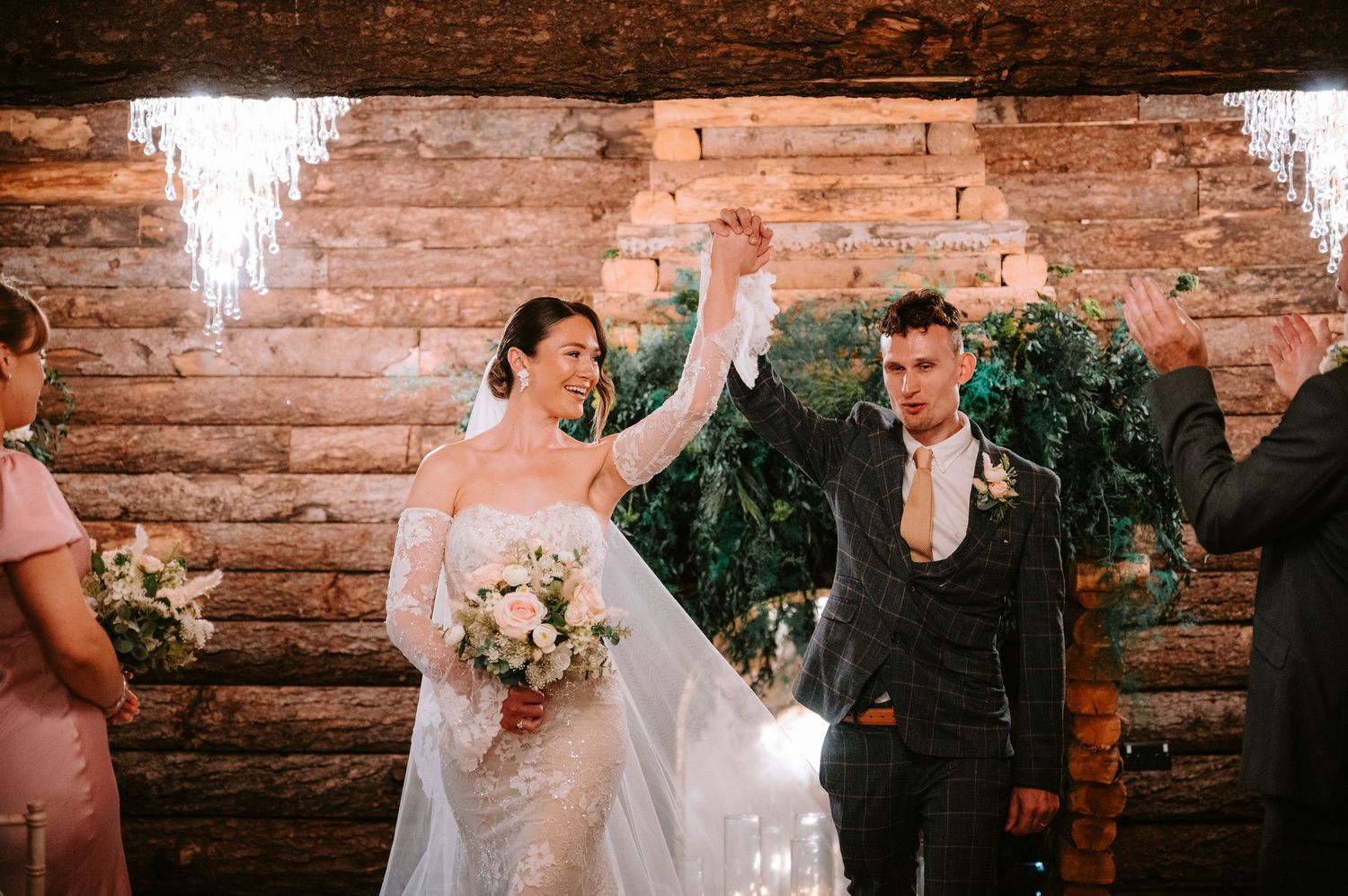 Newlyweds celebrate during a wedding ceremony in a rustic brick-walled venue with joyful expressions.