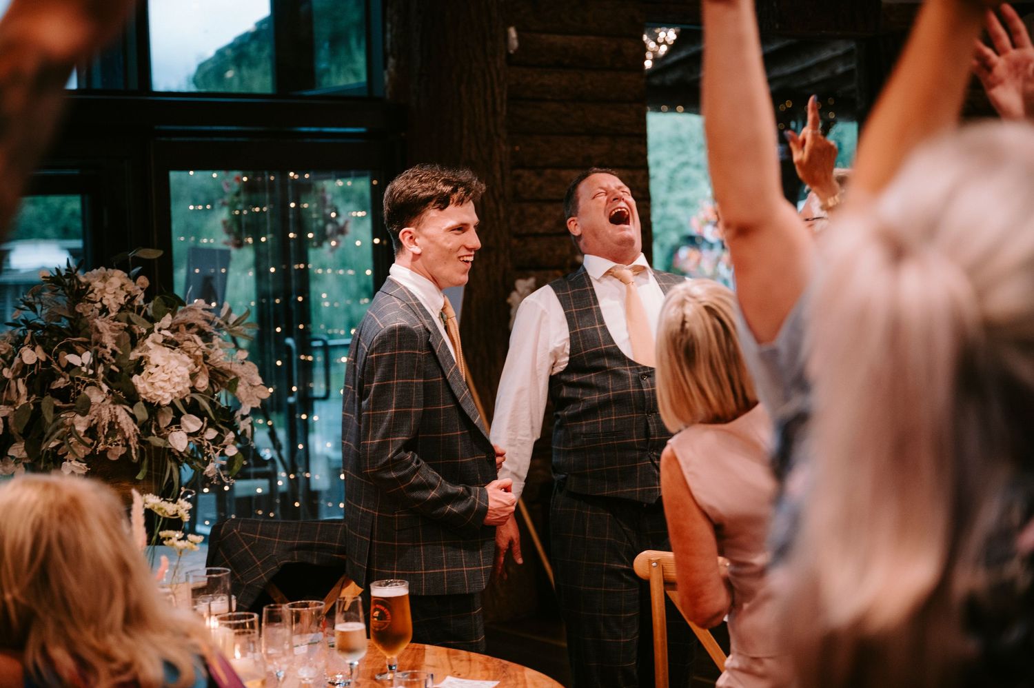 Wedding guests dance and celebrate during a lively reception in a dimly lit venue.