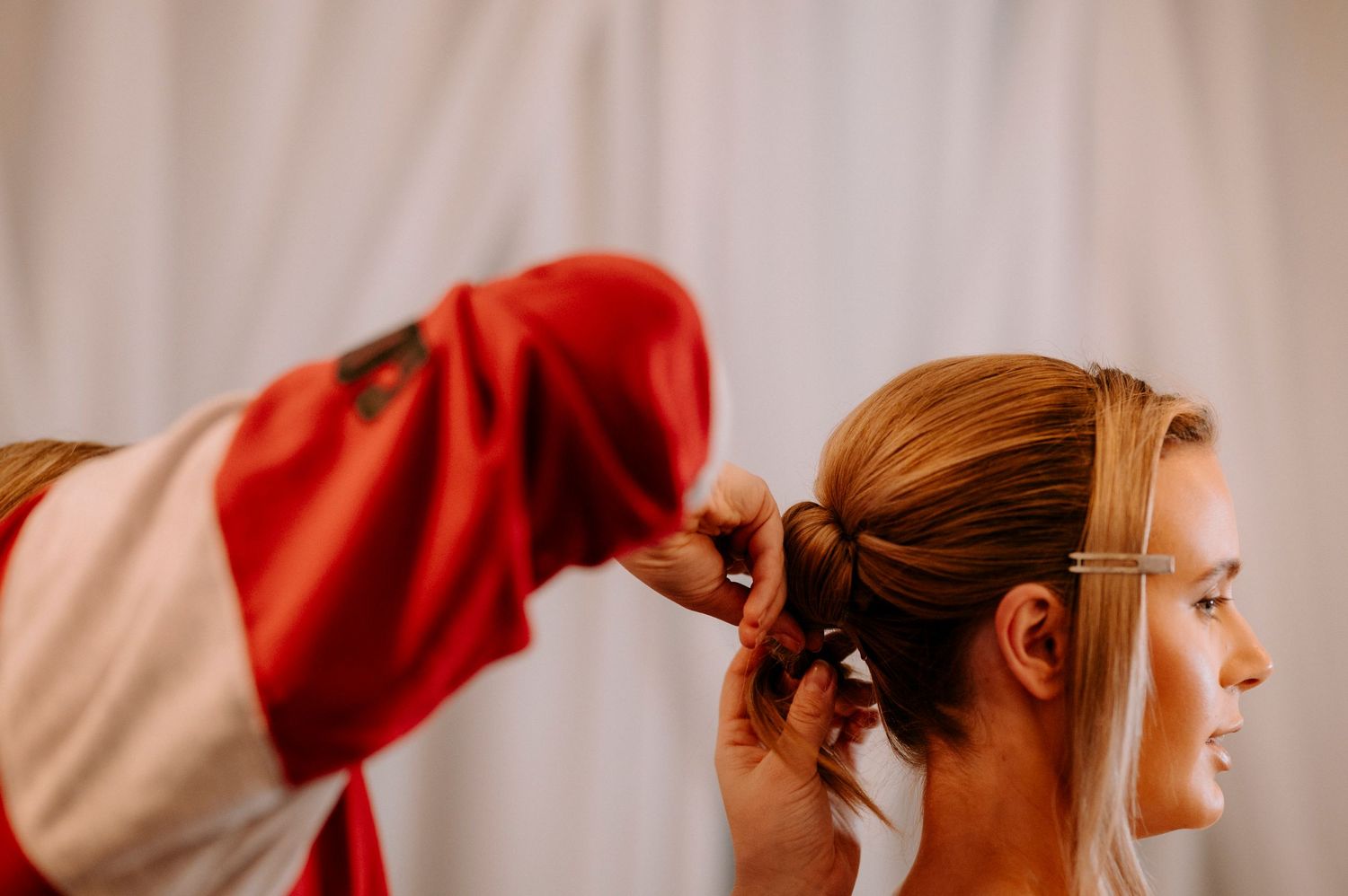 Close-up of hands styling hair against a white backdrop.