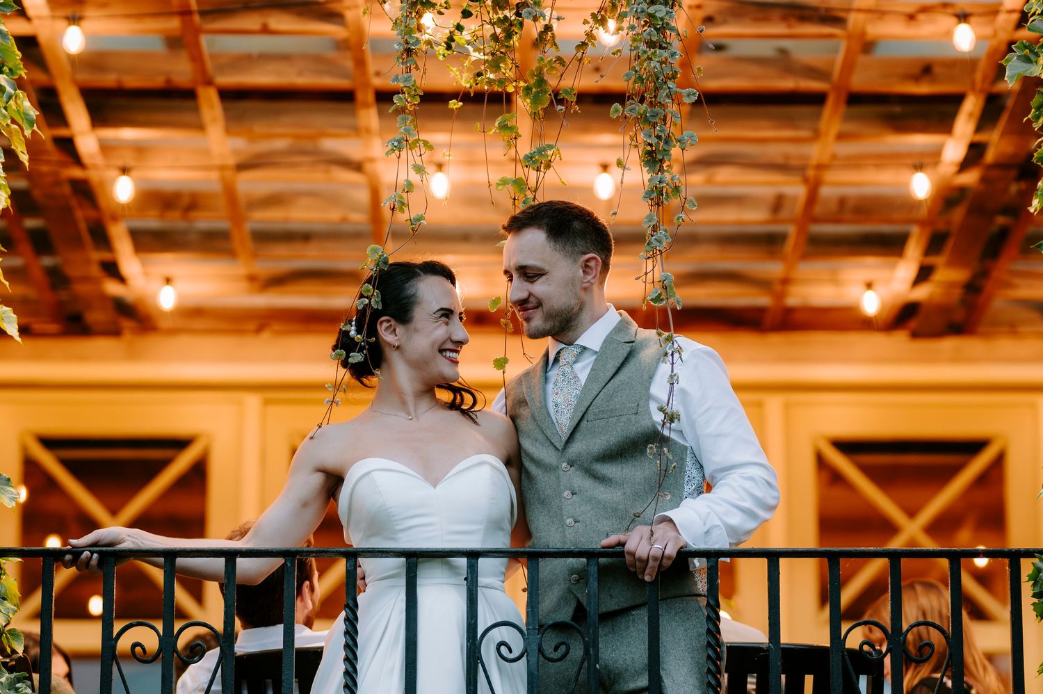 Couple sharing an intimate dance under warm lighting and hanging greenery at their reception.