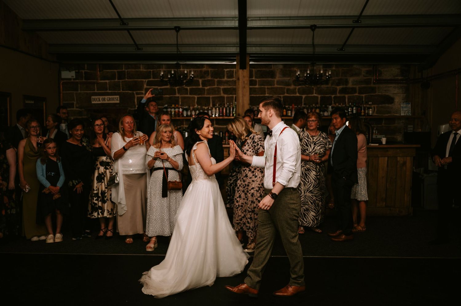 Wedding reception dance party in dimly lit rustic venue.
