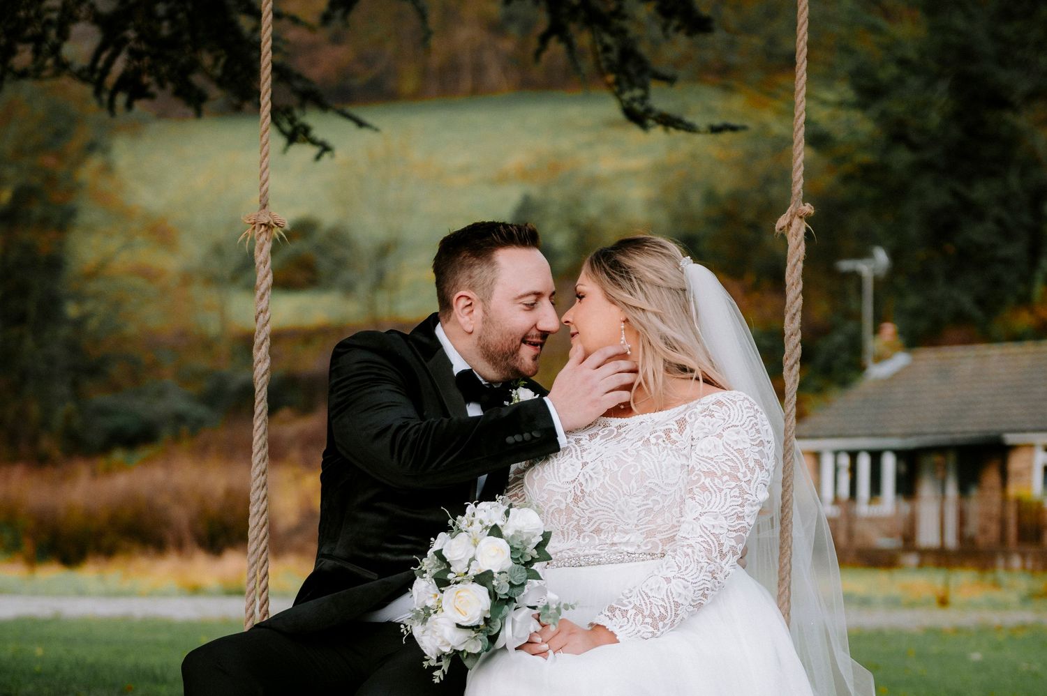 A joyful moment shared between newlyweds on a wooden swing outdoors.
