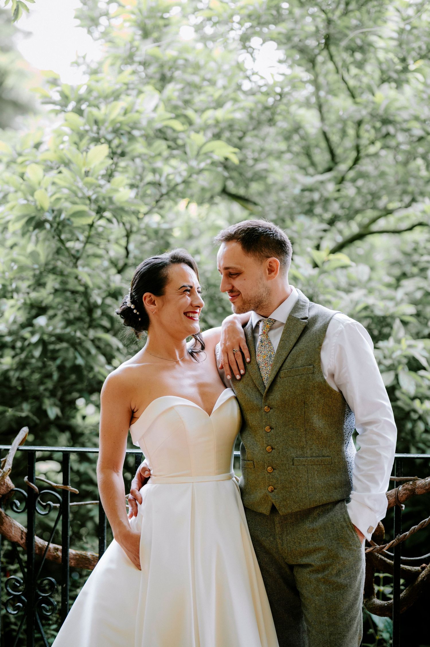 A romantic wedding portrait showing a couple sharing a joyful moment together in a lush garden setting.