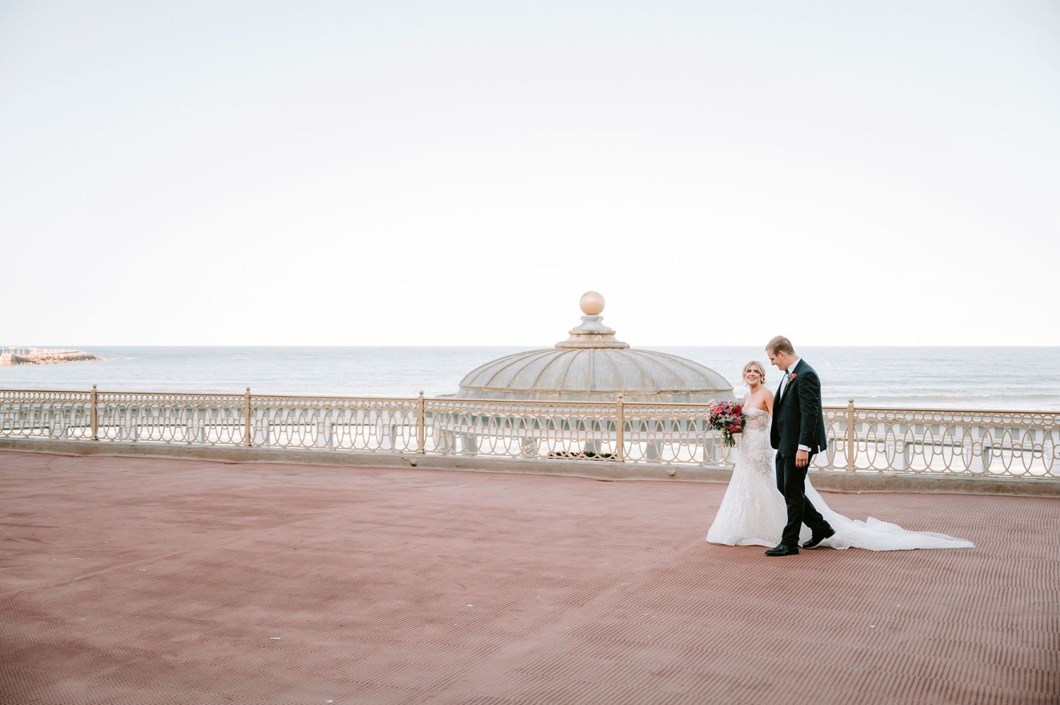 Romantic seaside wedding portraits along an oceanfront promenade.