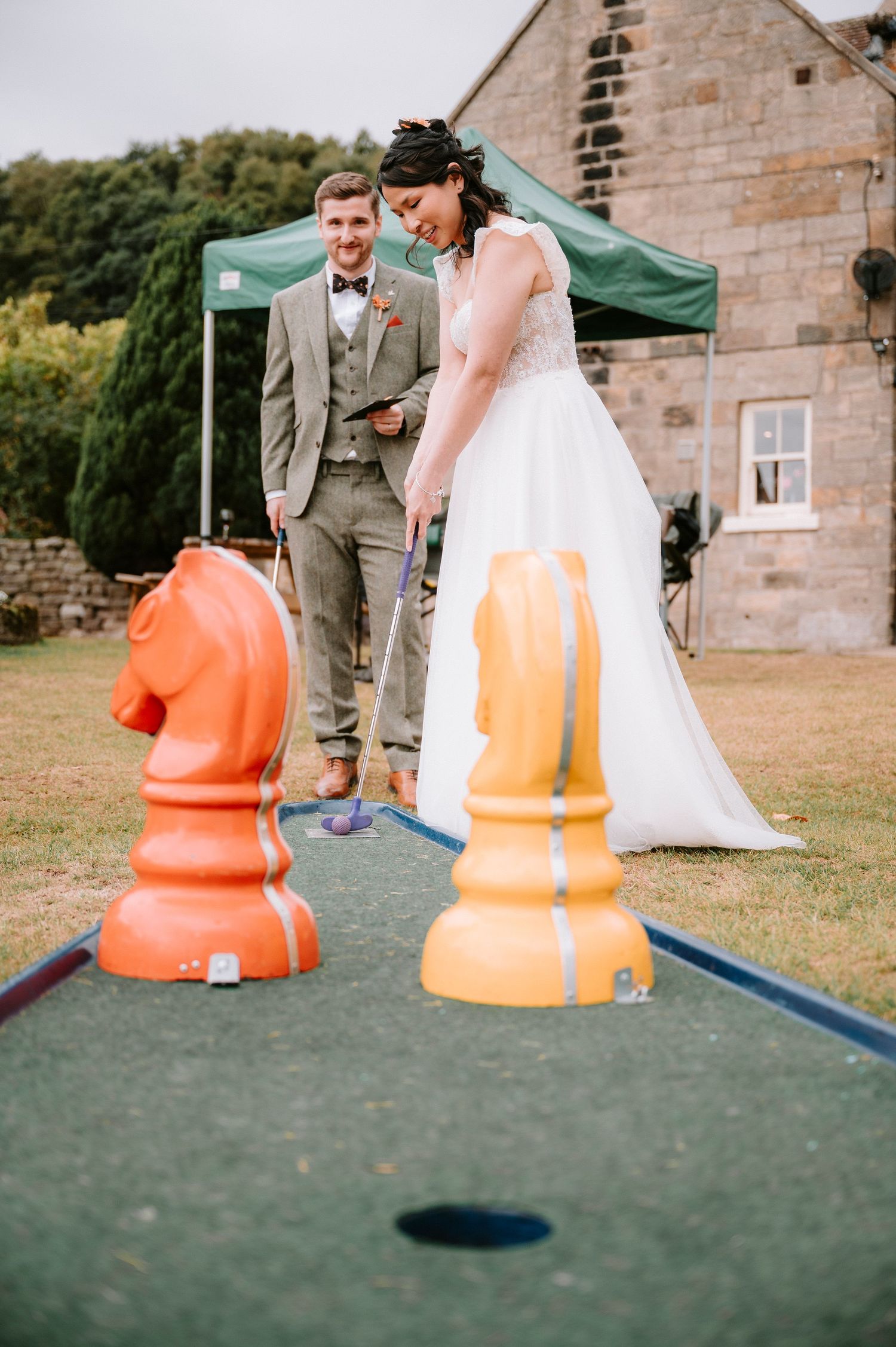 Couple plays on orange space hoppers at an outdoor wedding venue.
