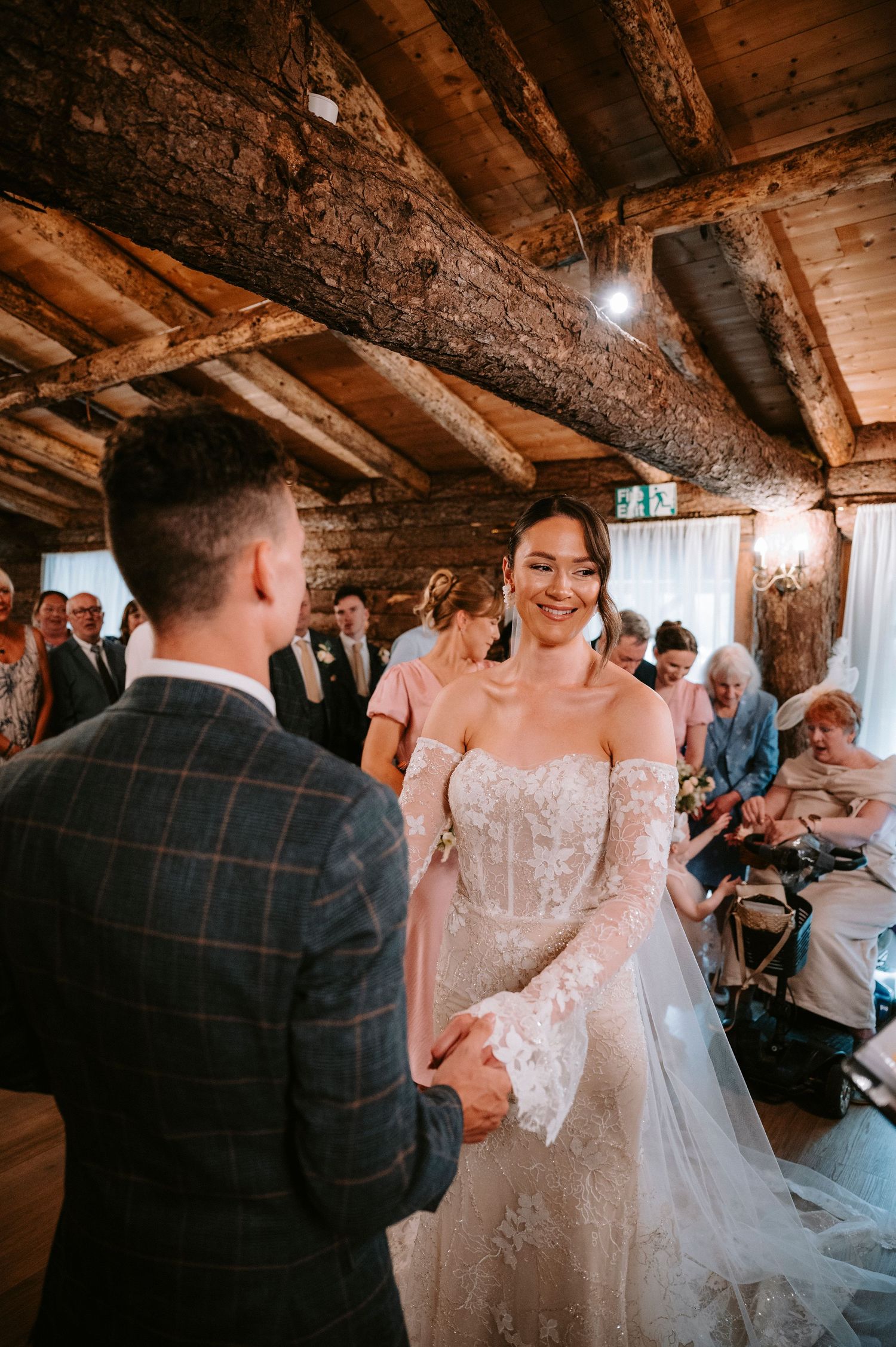 Wedding ceremony taking place in a rustic wooden barn with exposed beams and natural lighting.