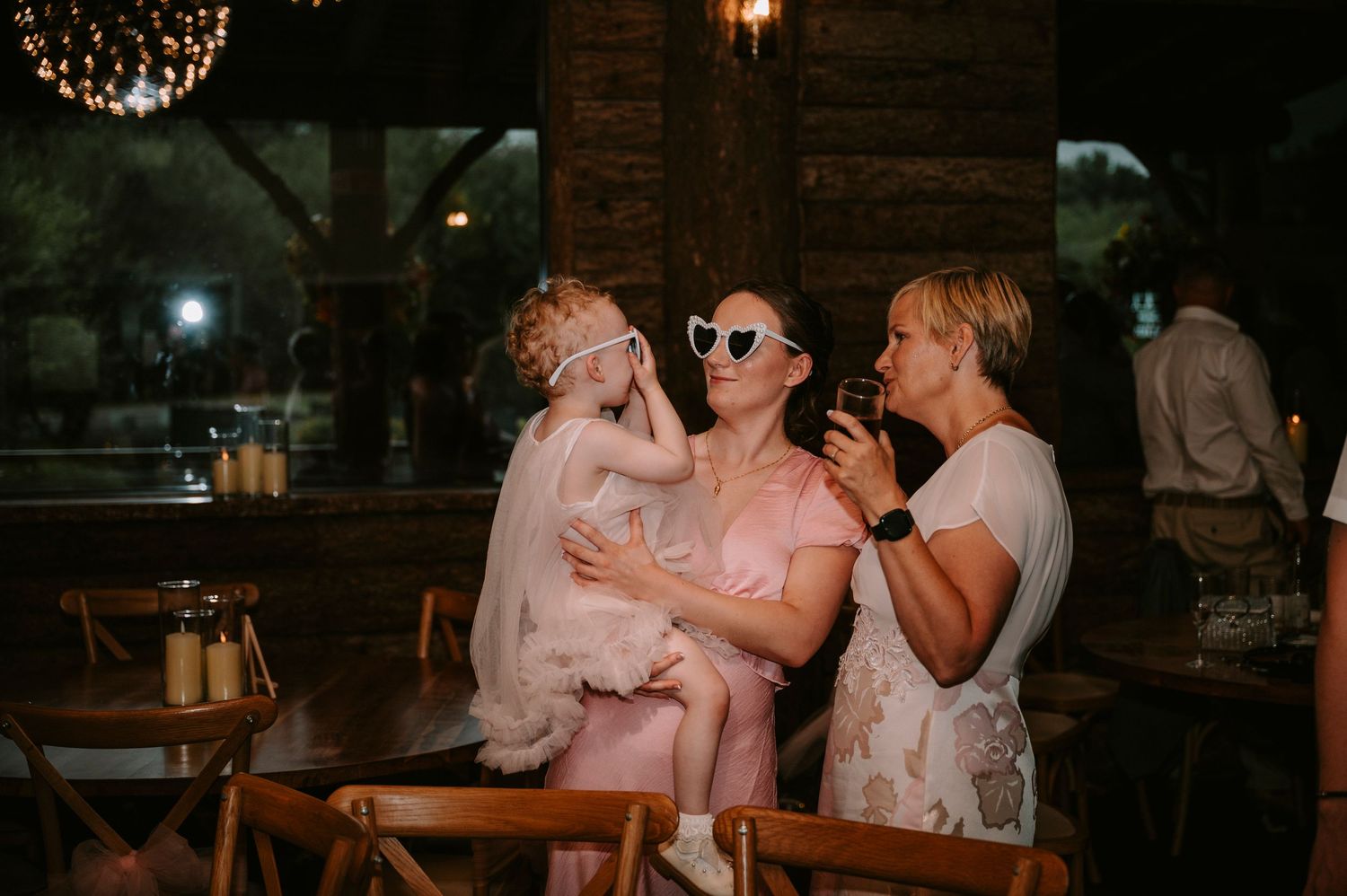 Wedding reception guests enjoying themselves in warm ambient lighting.