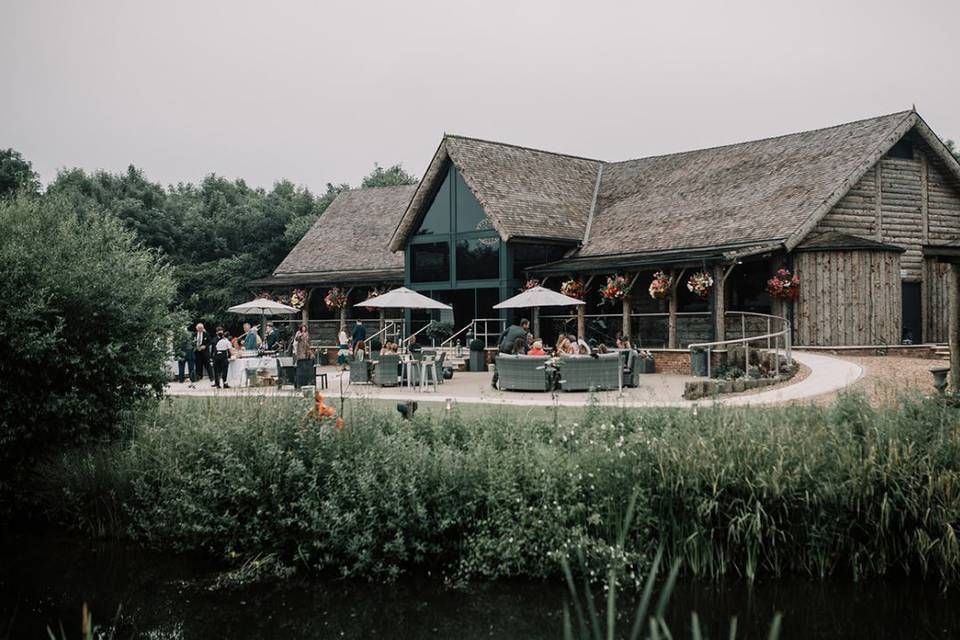 Rustic wooden buildings and structures nestled among trees and greenery at a countryside venue.