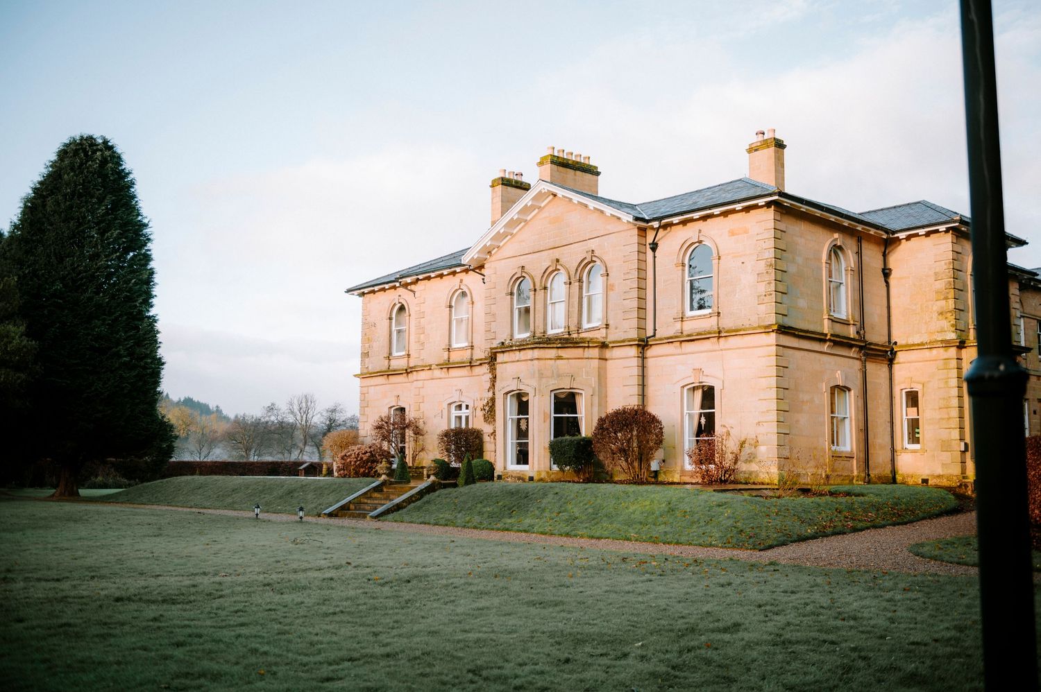 A panoramic view of an elegant stone mansion wedding venue with manicured grounds.