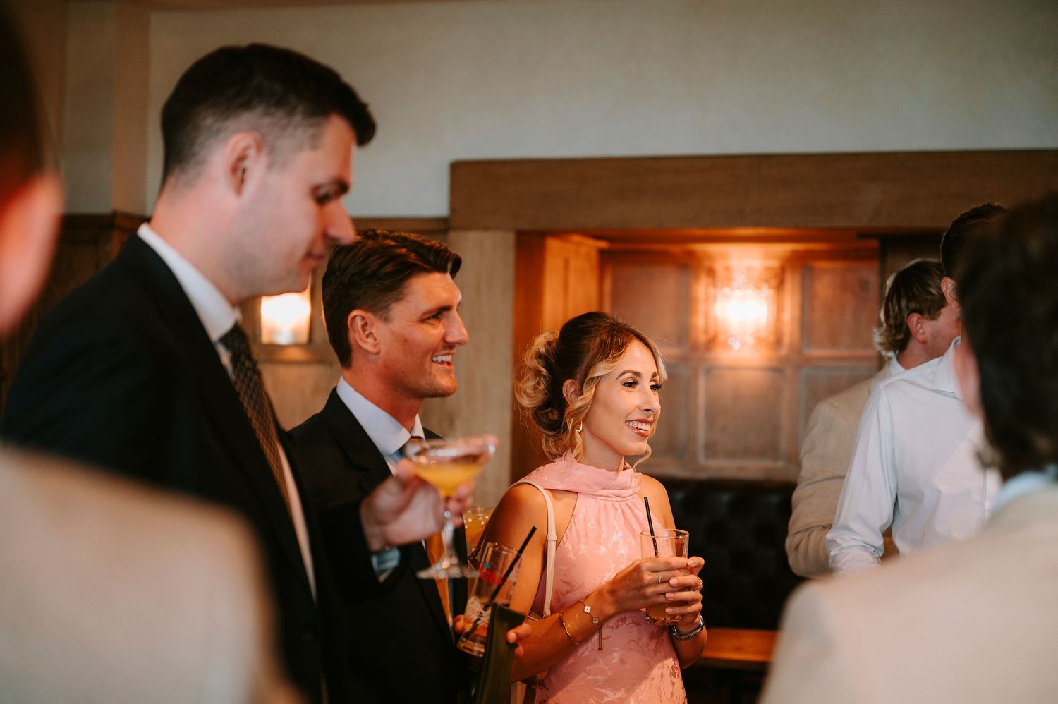 Guests enjoying drinks and conversation at an indoor wedding reception.