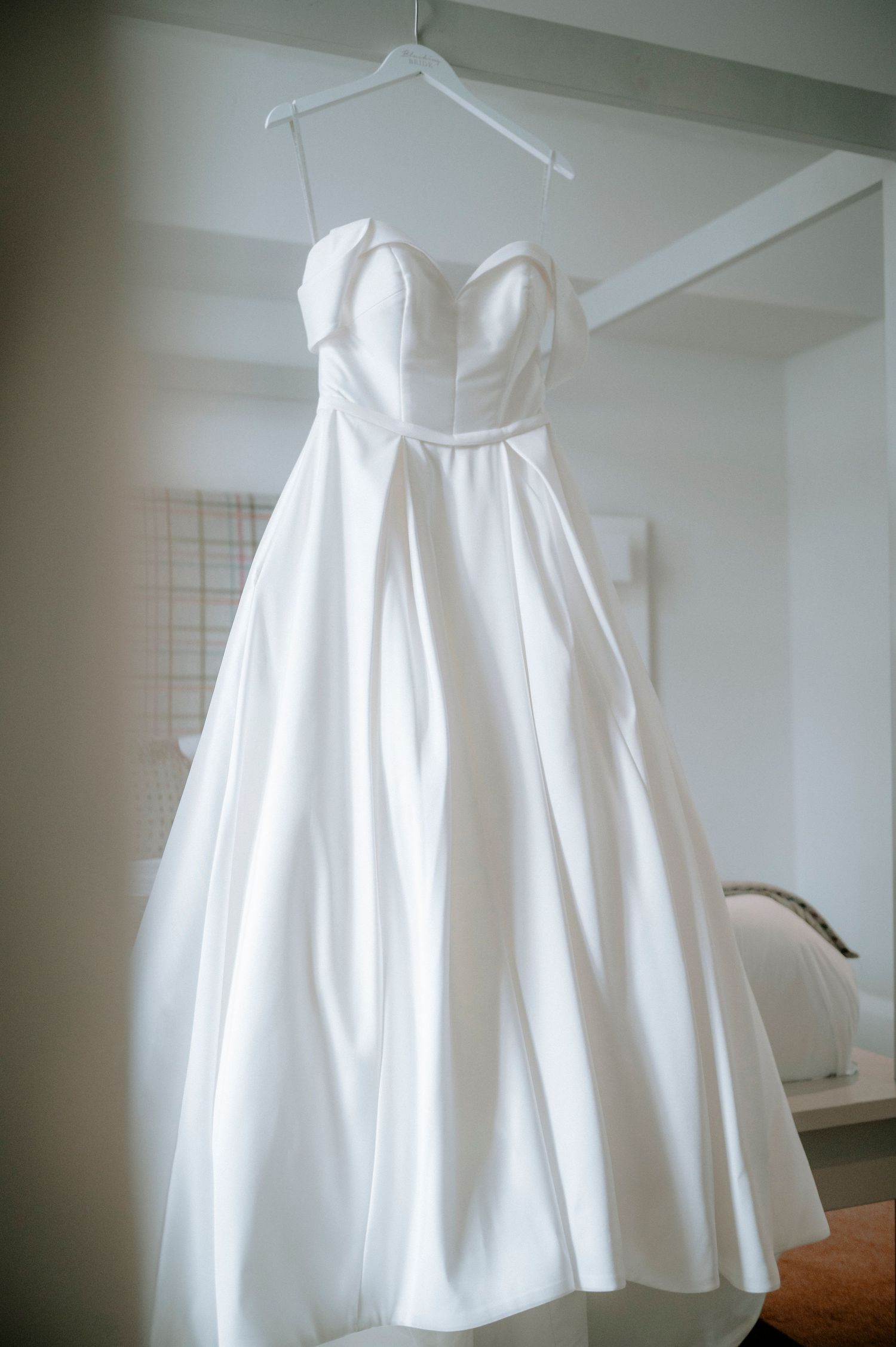 White wedding dress hanging on display showing its full skirt and elegant design.