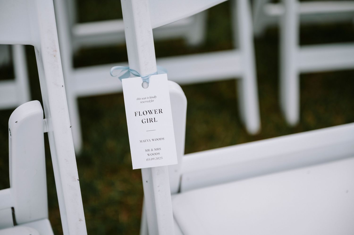 White folding chairs set up for outdoor wedding ceremony with reserved signs attached.